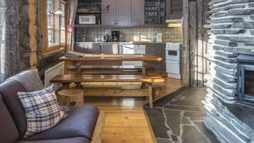A cozy cabin interior with a wooden bench, a sofa, and a stone fireplace.