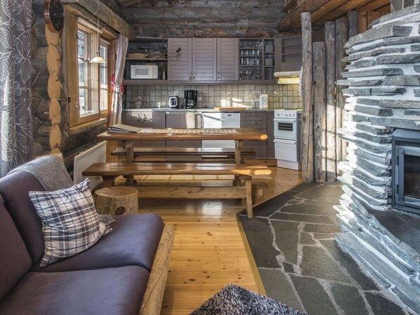 A cozy cabin interior with a wooden bench, a sofa, and a stone fireplace.