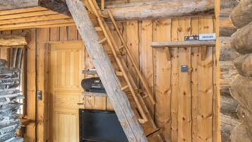 L’intérieur d’un chalet en bois, avec un escalier en bois, une porte et un téléviseur posé sur un meuble en bois.
