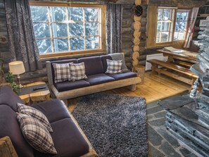 A cozy log cabin interior with a sofa, a dining table, and a fireplace.