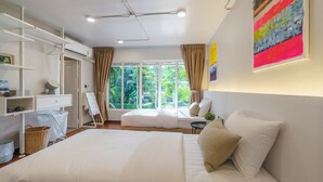 A modern hotel room with a large bed, a seating area by the window, and a white wardrobe.