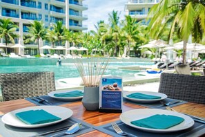 A dining table set with plates, cutlery, and napkins, with a menu stand in the center. - On sale! Serene retreat beachside 3 BR villa w/ workspace and bathtubs  (Da Nang)