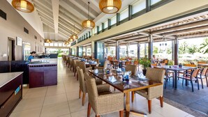 A spacious restaurant with high ceilings, large windows, and wicker chairs.