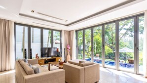 A spacious living room with large sliding glass doors leading to a pool area, a flat-screen TV, and a comfortable seating arrangement.