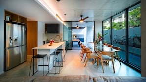 A modern kitchen with a central island, bar stools, and a dining area with wooden chairs.