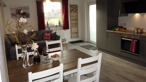 A modern kitchen with a dining table, chairs, and a sofa in the living area. - FeWo Frank Rudersberg, 1-3 people, (Rudersberg)