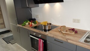 A modern kitchen with a wooden countertop, stainless steel appliances, and a variety of fresh vegetables. - FeWo Frank Rudersberg, 1-3 people, (Rudersberg)