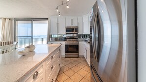 Una cocina moderna con armarios blancos, electrodomésticos de acero inoxidable, una isla grande y vistas al exterior.