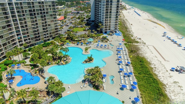Un resort con varias piscinas, una playa y edificios altos.