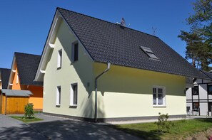 A two-story house with a sloped roof, a satellite dish, and a small window.