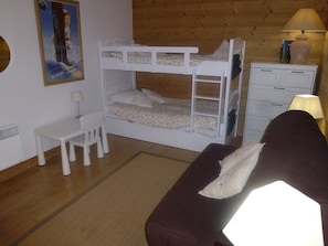 Quarto com beliche, escrivaninha, cadeira e cômoda.
