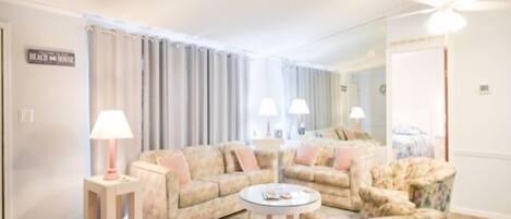 A living room with a sofa, armchairs, a coffee table, and lamps.