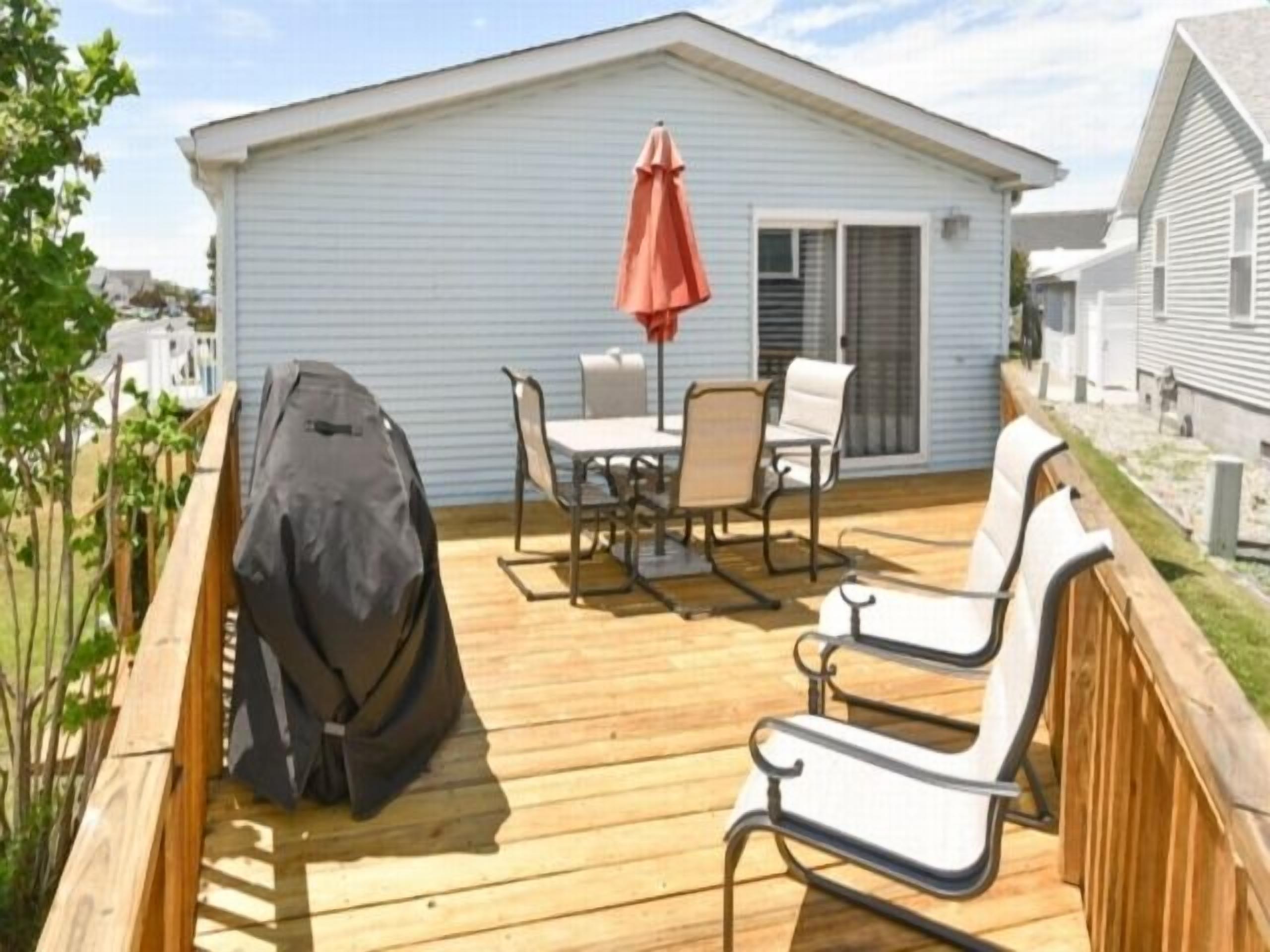 Une terrasse avec un barbecue, des chaises et une table.