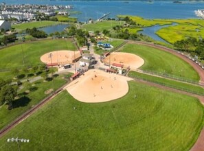 Une vue aérienne d’un terrain de baseball avec un stade, une rivière et des immeubles résidentiels en arrière-plan.