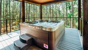 Un bain à remous sur une terrasse en bois, avec vue sur la forêt.