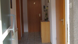 Ein Korridor mit gefliestem Boden, Holztüren und einem Heizkörper links.