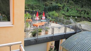 Eine Terrasse mit Sitzgelegenheiten im Freien, Blumentöpfen und Blick auf eine Hügelkuppe.