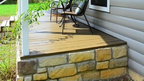 Eine überdachte Veranda mit Steinfassade, einem Tisch und Stühlen.