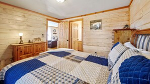 Ein Schlafzimmer mit Holzwänden, einem Bett, einem Schminktisch und einer Tür zu einem anderen Raum.