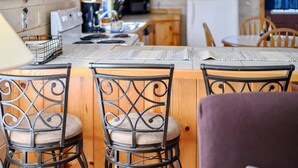 Eine Küche mit Holzschränken, einem Herd und einem Essbereich mit Tisch und Stühlen.