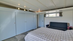 Ein Schlafzimmer mit Bett, Schlafsofa, Kleiderschrank und Fenster.
