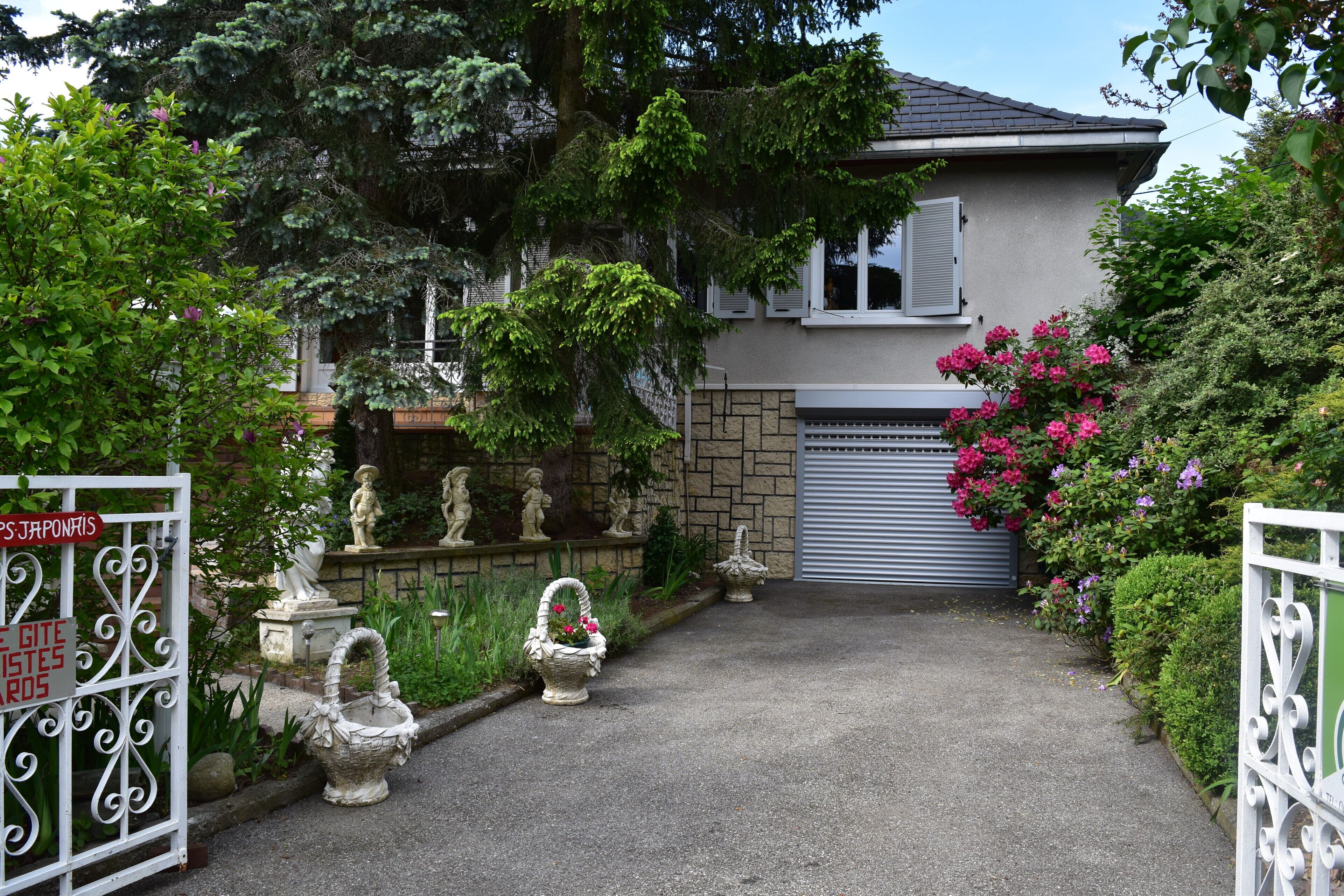 A house with a gated entrance, a stone wall, and a garage door.