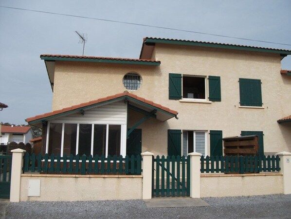 A two-story house with a garage, a fenced front yard, and a satellite dish. - Cozy Villa for 4 Near Beach with Terrace & Private Parking (Vieux-Boucau-les-Bains)
