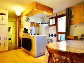 Une cuisine compacte dotée d’un îlot central, d’une table à manger et offrant une vue sur l’extérieur.