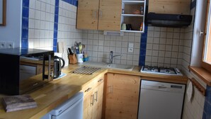 Eine kleine Küche mit Holzausstattung, einem integrierten Geschirrspüler und einem Gasherd.