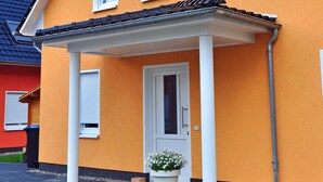 A two-story building with a sign reading "Ferienhaus Müritzwelle". - 3 room first floor - Apartment Ferienhaus Müritzwelle - Ferienwohnungen / (Röbel/Müritz)