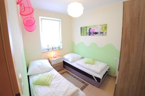 Ein Schlafzimmer mit zwei Betten, einem Fenster, einem Nachttisch und einem an der Wand befestigten Kunstwerk.