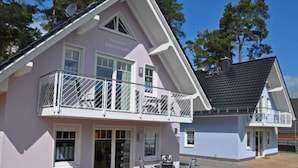 En toetagers bygning med en balkon og et overdækket udendørs siddeområde, under en klar himmel.