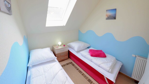 Une chambre avec deux lits, une table de chevet, une fenêtre et un radiateur.