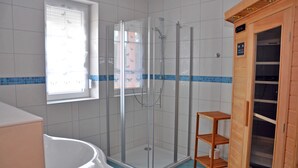 A modern bathroom with a glass-enclosed shower, a toilet, and a wooden sauna cabinet. - 3 room first floor - Apartment Ferienhaus Müritzbrise - Ferienwohnungen / (Röbel/Müritz)