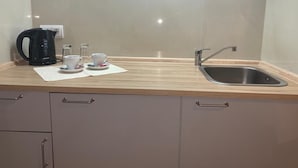A kitchen with a sink, a kettle, and two cups on the counter. - City Apartments in Köln am Rheingarten (Cologne)