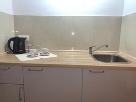 Una cocina con un lavabo, una tetera y dos tazas sobre la encimera.