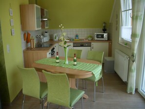 Une cuisine équipée d’une table à manger, de chaises, d’un four à micro-ondes et d’une fenêtre avec des rideaux.