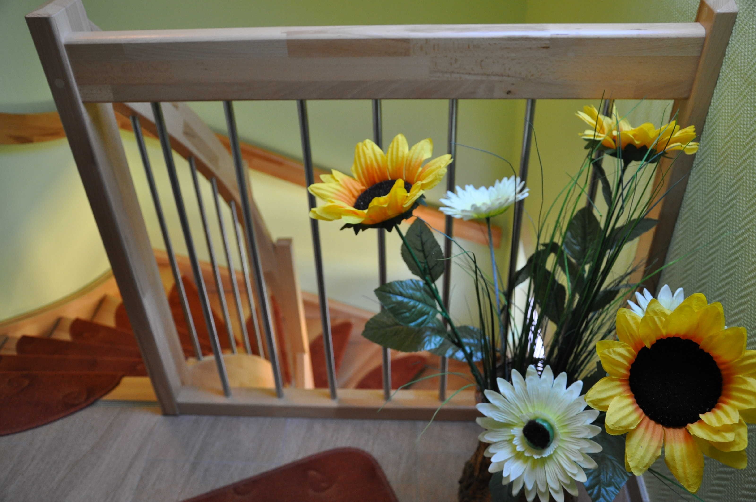 Een houten leuning met een bloemstuk.