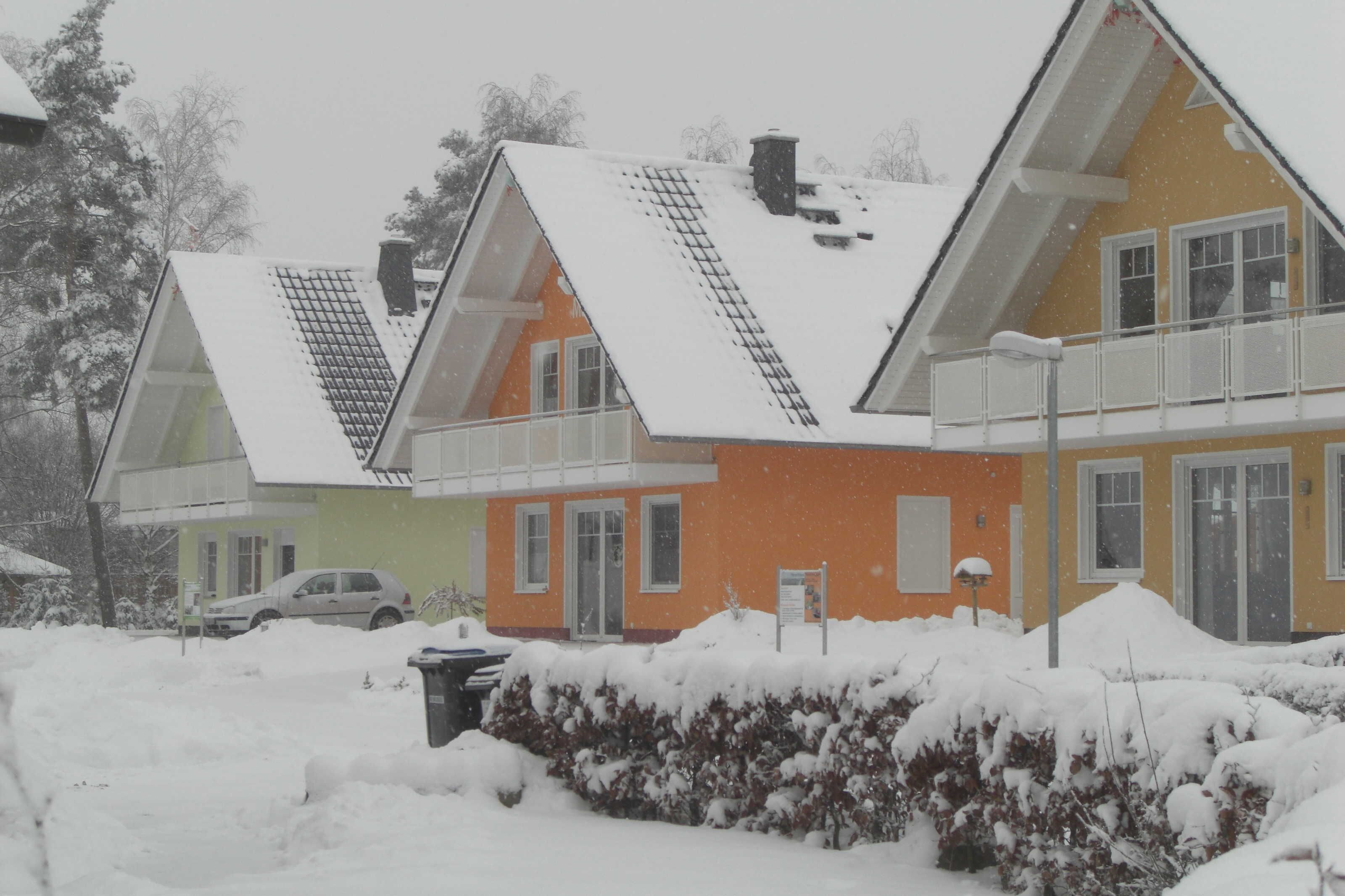 Une rangée de maisons aux toits inclinés, et le sol couvert de neige.