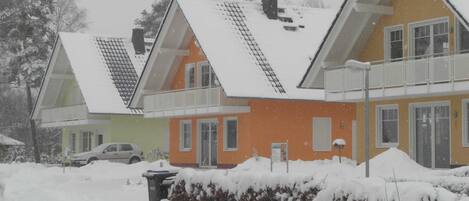 A row of houses with sloped roofs and a snow-covered ground.