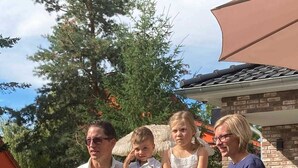 Una famiglia di quattro persone all'aperto, con una casa sullo sfondo.