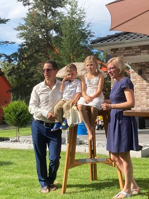 A family of four outdoors with a house in the background.