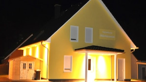 A yellow building with a sign reading "Ferienhaus Müritzzonne" at night. - 3 room upper floor - Apartment Ferienhaus Müritzsonne - Ferienwohnungen / (Röbel/Müritz)