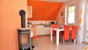 A kitchen with a stove, microwave, and dining area with chairs. - 3 room upper floor - Apartment Ferienhaus Müritzsonne - Ferienwohnungen / (Röbel/Müritz)