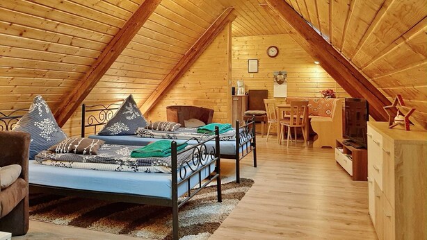 A cozy attic bedroom with a sloped ceiling, a bed, a desk, and a chair.