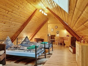 A cozy attic bedroom with a sloped ceiling, a bed, a desk, and a chair.
