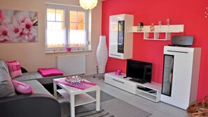 Un salon avec un canapé, une table basse, un téléviseur et une cheminée.