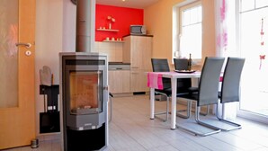Une cuisine moderne avec un poêle à bois, une table à manger avec des chaises et un mur d’accent d’un rouge vif.