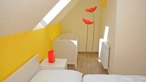 A small, bright room with a sloped ceiling, a white bed, a small table, and a radiator. - 3 room upper floor - Apartment Ferienhaus Müritzlust - Ferienwohnungen / (Röbel/Müritz)