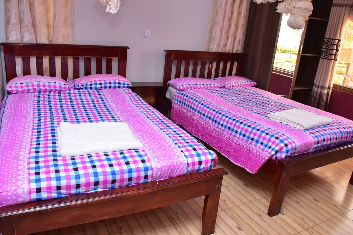 Dos camas de madera con ropa de cama a cuadros y toallas blancas.